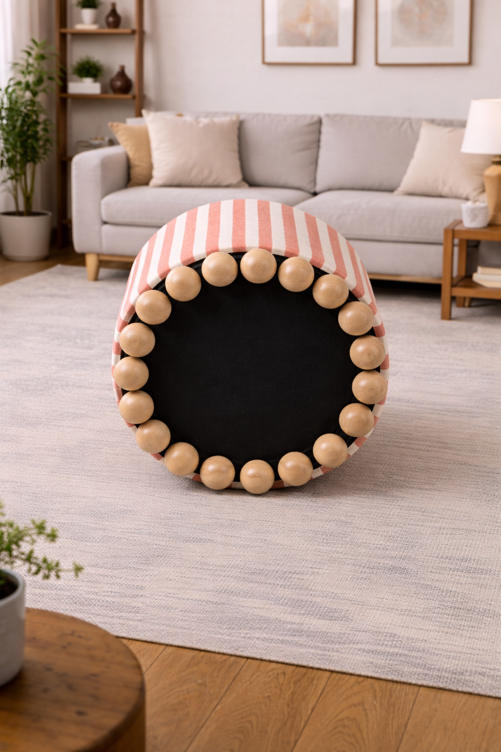 Close-up of a cylindrical fabric ottoman featuring a unique ball-style wooden base, highlighting the quality craftsmanship of a leading ottoman manufacturer