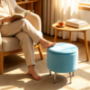Light blue velvet oval storage ottoman placed on a sunlit patio next to wooden outdoor lounge chairs.
