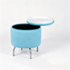 Modern light blue oval velvet storage footstool styled next to a blue sofa in a contemporary living space.