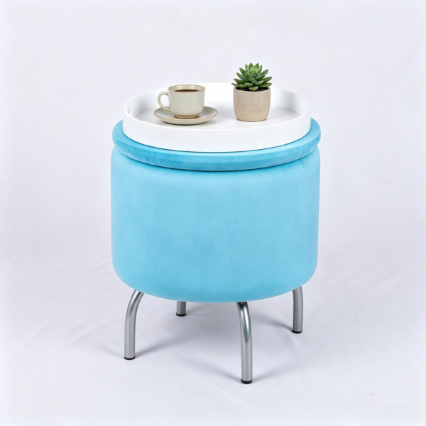 Light blue velvet round storage ottoman with metal legs, featuring a white wooden tray top holding a coffee cup and succulent plant on a plain background.