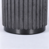 Dark gray pleated velvet storage stool placed next to a cozy bed in a warm bedroom setting.