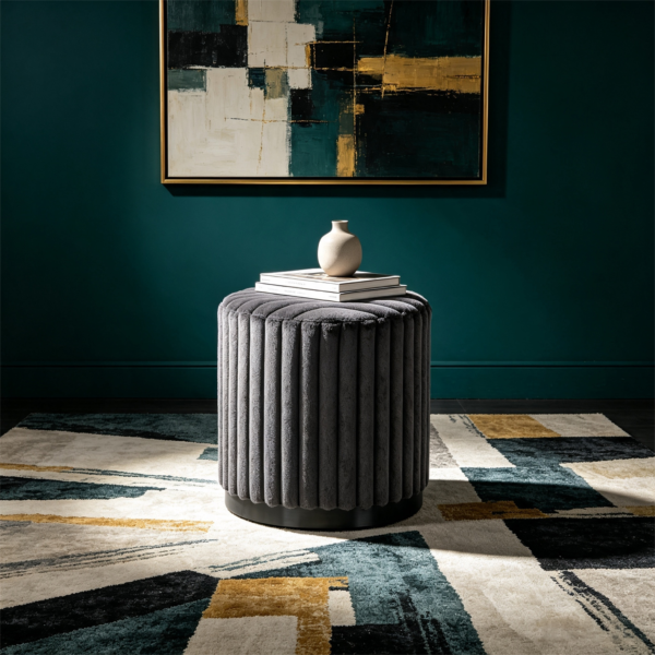 Dark gray fluted velvet round storage ottoman stool in a moody modern room setting.