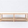Beige upholstered rectangular ottoman coffee table featuring carved wooden legs and a bottom storage shelf.