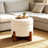 White teddy boucle round storage ottoman styled in a bright modern living room next to a wooden side table