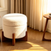 White teddy boucle round storage ottoman footstool with wooden legs in a cozy living room setting