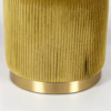 Close-up of a mustard yellow pleated velvet round storage ottoman with a brushed gold metal base