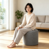 Close-up view of the minimalist leather accent handle on a grey round fabric storage ottoman